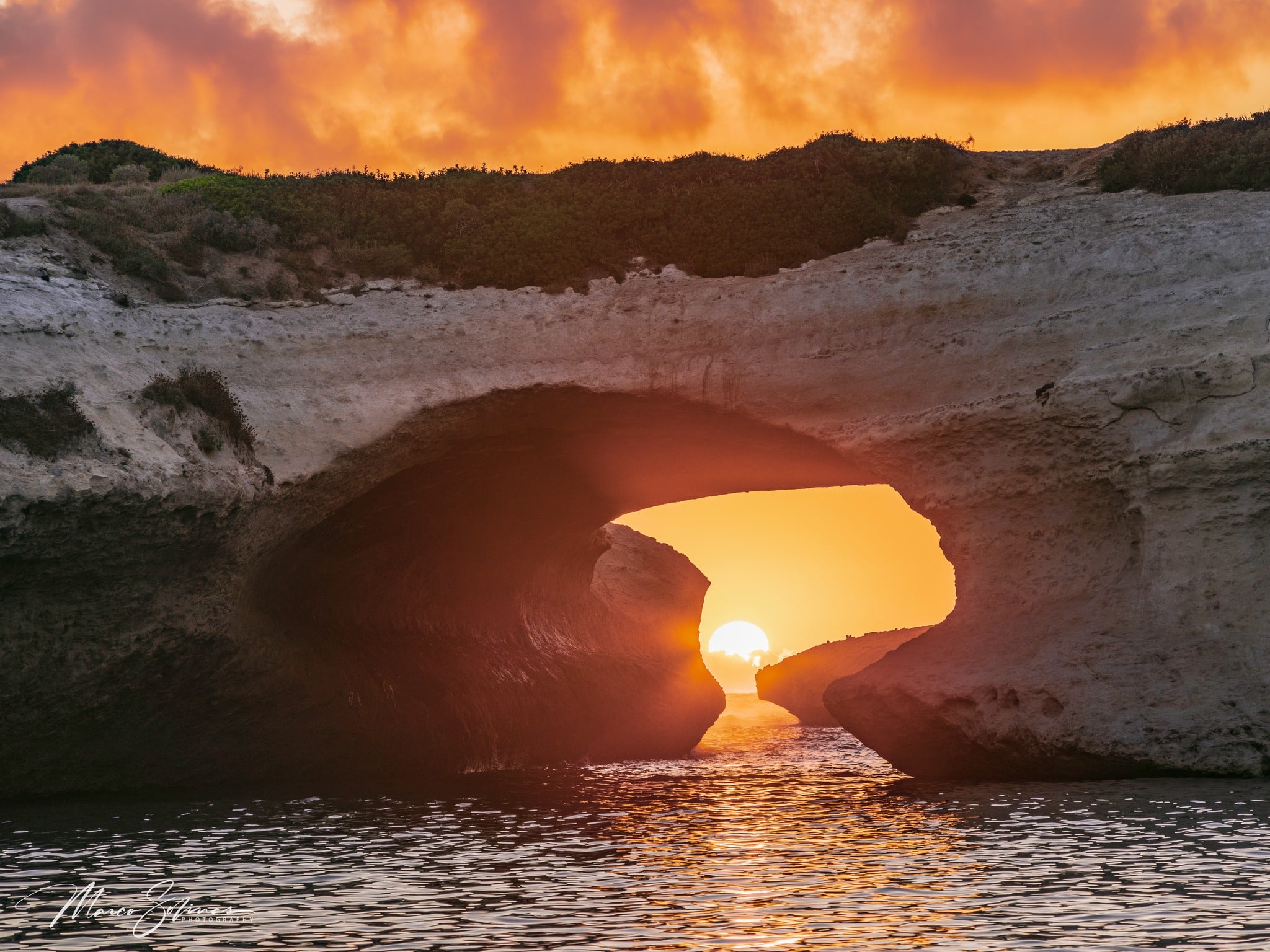 Un fotografo su una vetta rocciosa domina un vasto paesaggio montano.